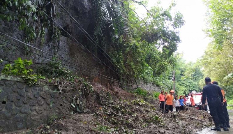 NusaBali.com -  Petugas saat mengevakuasi pohon tumbang dan material longsor di jalan raya Dusun Uma Salakan, Desa Takmung, Kecamatan Banjarangkan, Klungkung, Senin (6/5). .-DEWA